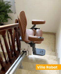 Monte-escalier électrique installé dans une villa à Rabat sur escalier en marbre avec rampe en bois, siège ergonomique et rail fixé sur les marches